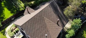 A close-up of a house roof with missing shingles and rusted metal flashing after a rain shower.